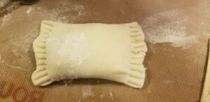 Uncooked hand pie with pastry edges crimped down with a fork