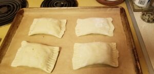 Hand pies on a sheet pan waiting for egg wash